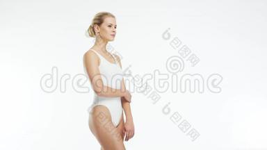 年轻，美丽，苗条和健康的金发女孩穿着白色泳衣，涂上<strong>护肤</strong>霜。 按摩、<strong>护肤</strong>、保健